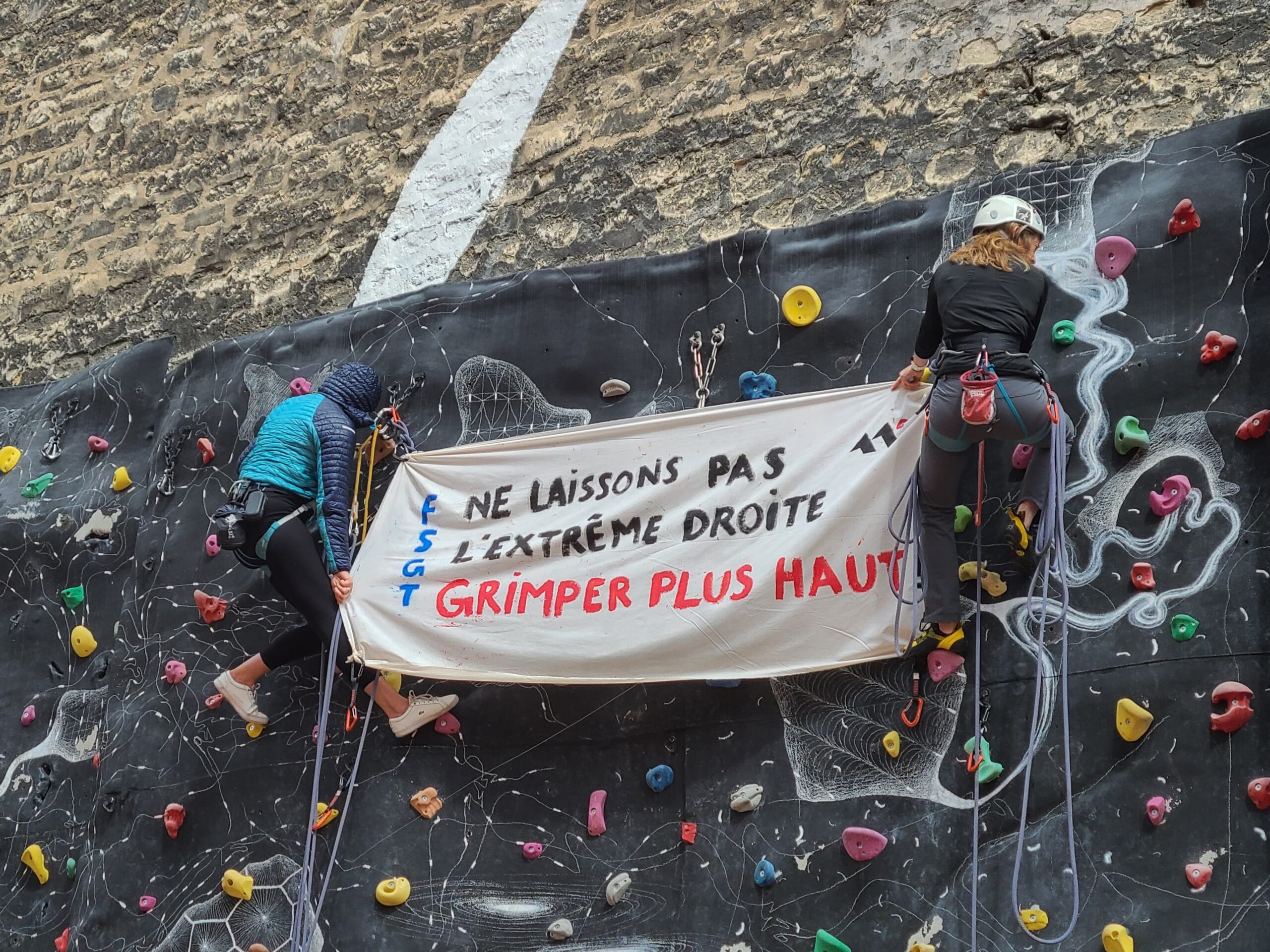 Banderole "ne laissons pas l'extrême droite grimper plus haut" tenue par deux femmes en haut du mur d'escalade